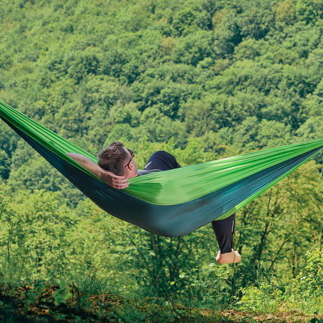 Hamac hikerjoy forest green montat între copaci, cu pădure în fundal
