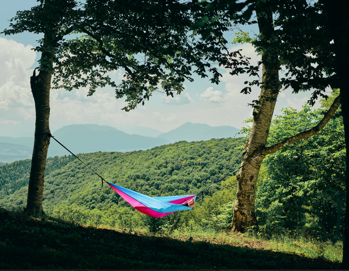 Persoană relaxându-se în hamacul hikerjoy roz cu bleu în natură