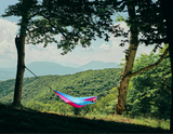 Persoană relaxându-se în hamacul hikerjoy roz cu bleu în natură