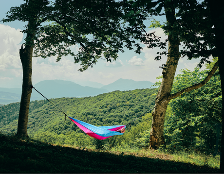 Persoană relaxându-se în hamacul hikerjoy roz cu bleu în natură