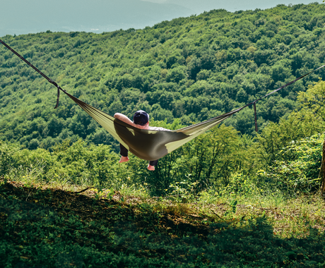 Persoană relaxându-se în hamacul hikerjoy PRO green army în natură