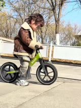 Copil pe bicicletă fără pedale Velovity verde, în parc
