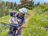 Mamă și copil cu bicicleta MTB și scaun frontal pentru copii, pe traseu montan