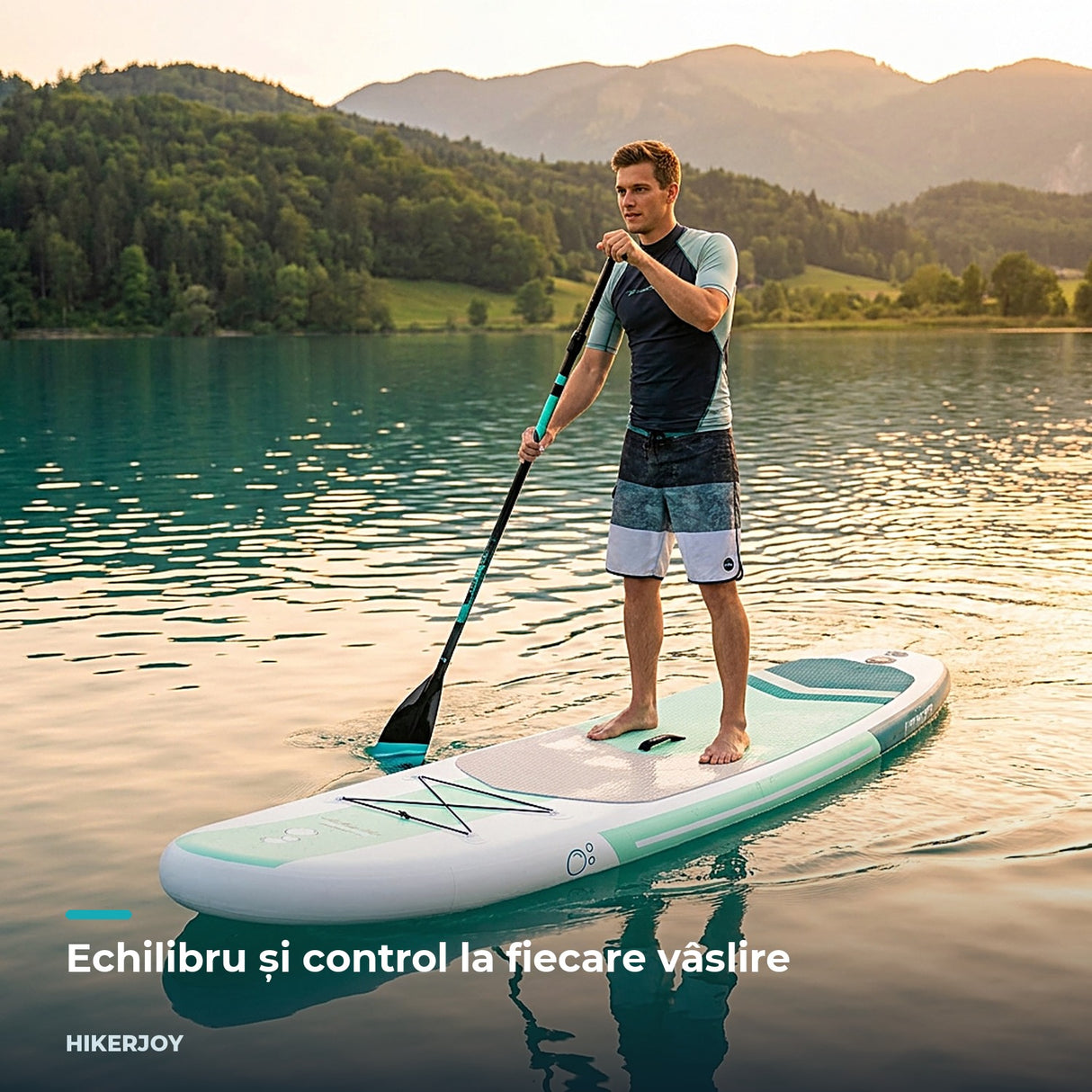 Bărbat pe placa SUP Sparkwave alb-verde, vâslind pe lac la apus