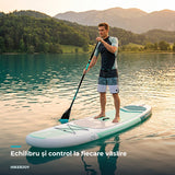 Bărbat pe placa SUP Sparkwave alb-verde, vâslind pe lac la apus